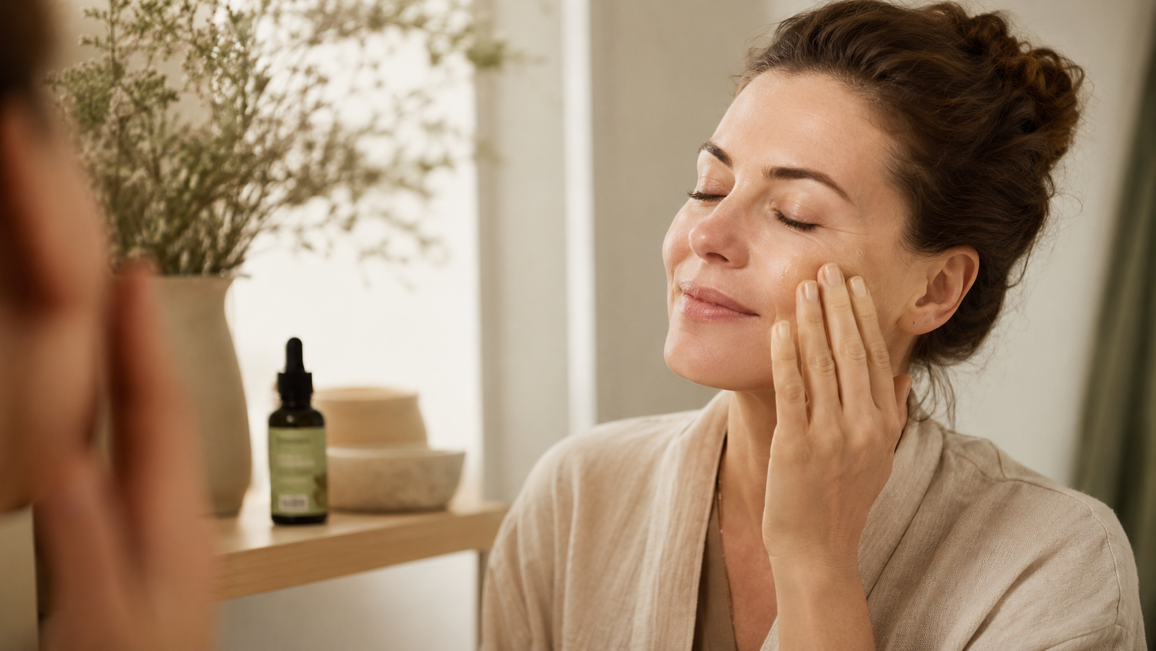 Frau trägt sanft ein CBD-Serum auf ihre Wange auf und pflegt ihre Haut in einer ruhigen, warmen Wellness-Atmosphäre mit natürlichem Licht.