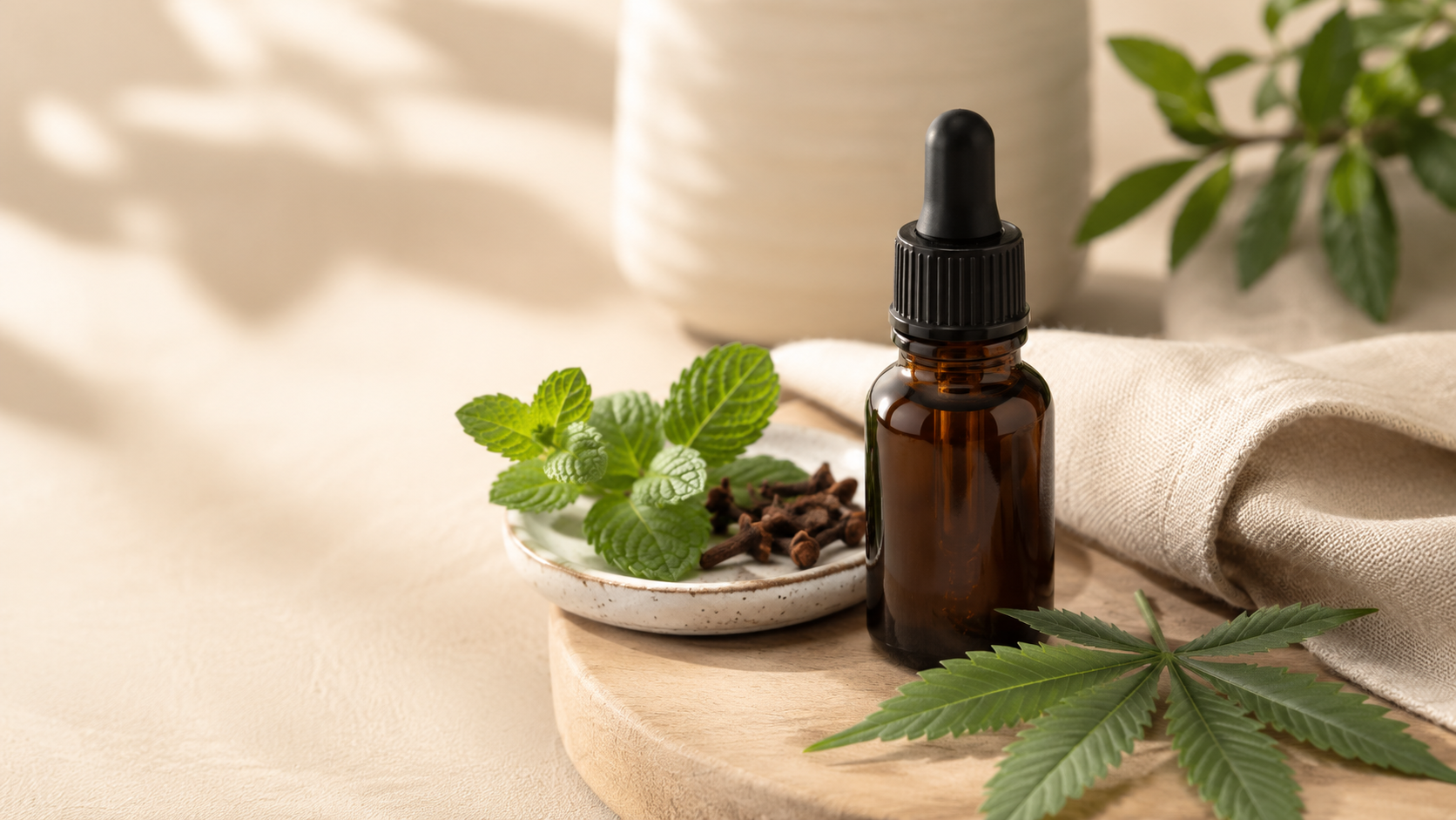 Amber CBD oil dropper bottle with fresh mint, cloves, a linen cloth, and a subtle hemp leaf on a warm wooden surface, representing gentle daily oral care in a calm natural wellness setting.